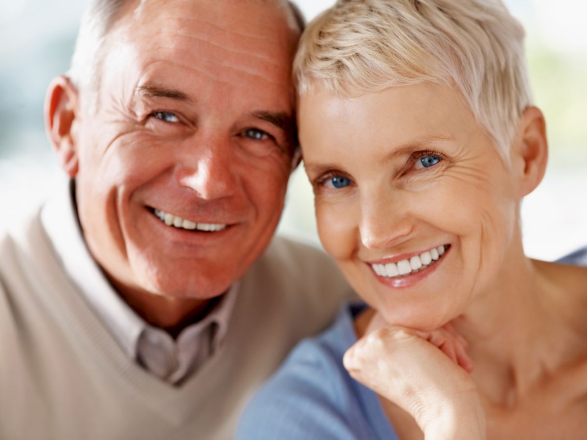 An older couple is smiling with their heads close together, exuding happiness and warmth.